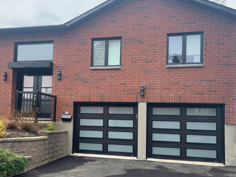 Garage spacieux doté de deux grandes portes Noir avec plusieurs fenêtres.