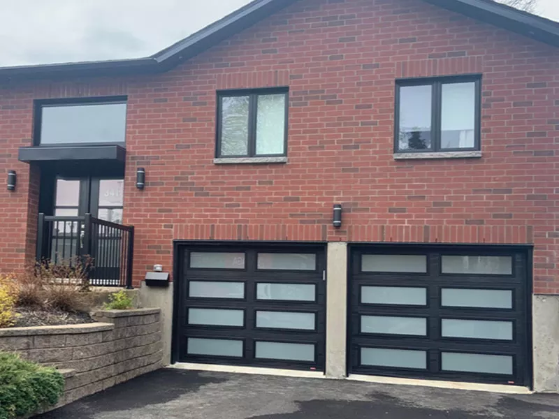 Garage spacieux doté de deux grandes portes Noir avec plusieurs fenêtres.